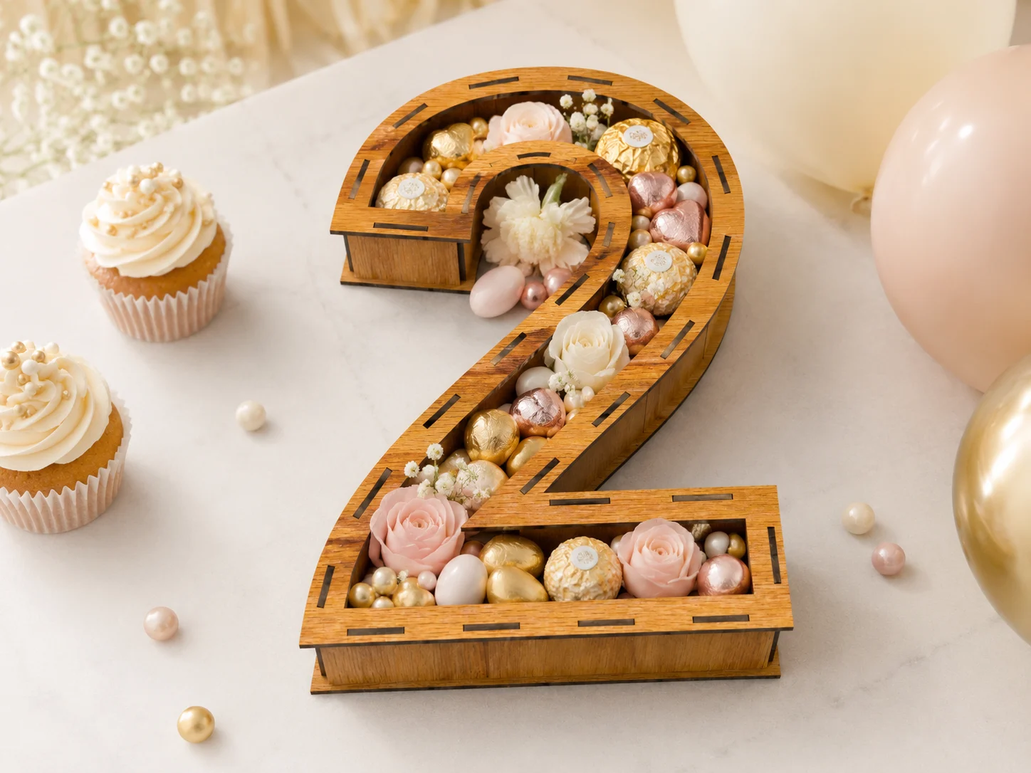 Wooden number 2 birthday box filled with pastel candies, chocolates and flowers, styled as elegant 2nd birthday party decor